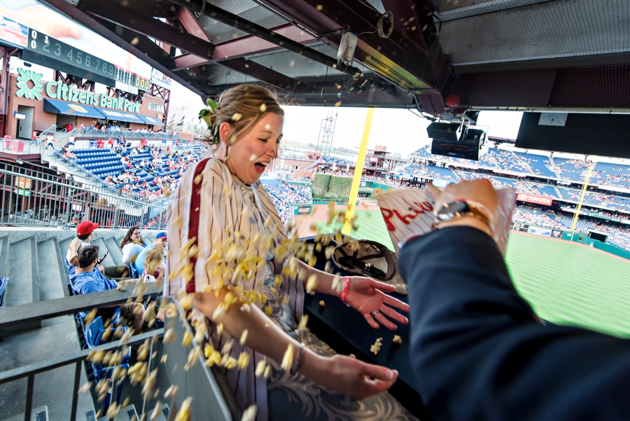A groom throwing popcorn on his bride at their Phillies game reception.